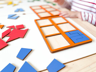 The child collects puzzles. Educational wooden toy for learning. Montessori materials. Fine motor skills, hand-eye coordination. Children's leisure, nursery.The concept of early development. squares. 