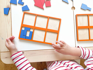 The child collects puzzles. Educational wooden toy for learning. Montessori materials. Fine motor skills, hand-eye coordination. Children's leisure, nursery.The concept of early development. squares. 
