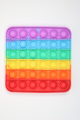 Vertical picture of square rainbow pop it fidget toy. Anti-stress push bubble. 