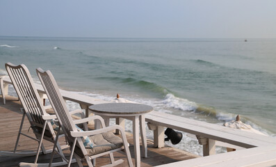 Closeup of a pairs of white wooden bed chair with sea and sky background.