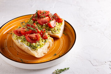 Breakfast with vegetarian sandwiches with avocado and tomatoes on a big orange plate
