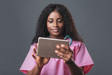 An African doctor consults a patient, makes a video call from a webcam on the tablet screen....