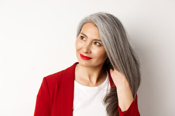 Beauty and haircare concept. Close up of elegant asian senior woman showing shiny and healthy grey...