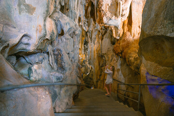A girl in a white dress stands in a cave. Ancient formations of stone. Touristic hiking route. Concept of excursions and attractions. (Cuceler magarasi) Tirilar, Sapadere, Alanya