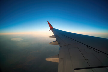 View of the wing of the plane through the window, sunset, clouds. Flight and tourism concept. Turkey