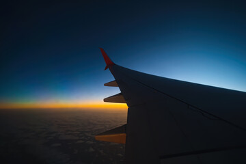 View of the wing of the plane through the window, sunset, clouds. Flight and tourism concept. Turkey
