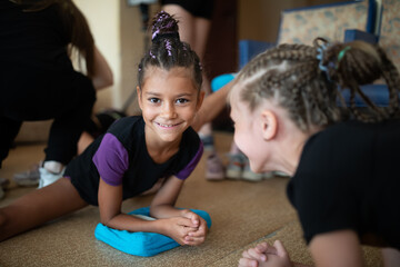 Girl gymnast smiling and stretching on training in sports camp