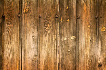 Naklejka premium Detail of old wooden door in brown tones with a lot of texture and rusty iron nails, with copy space at the bottom.
