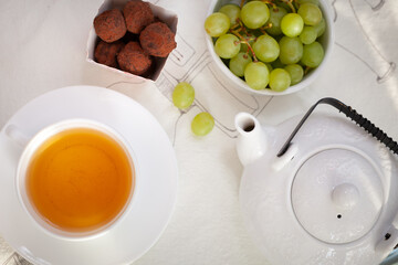 A cup of tea, Large white teapot, truffles and grapes for breakfast or afternoon tea for a buffet table and privacy.