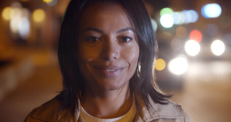 Beautiful mixed race woman posing outdoors on background with blurred lights