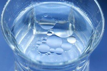 Oil drops on a water surface in a glass