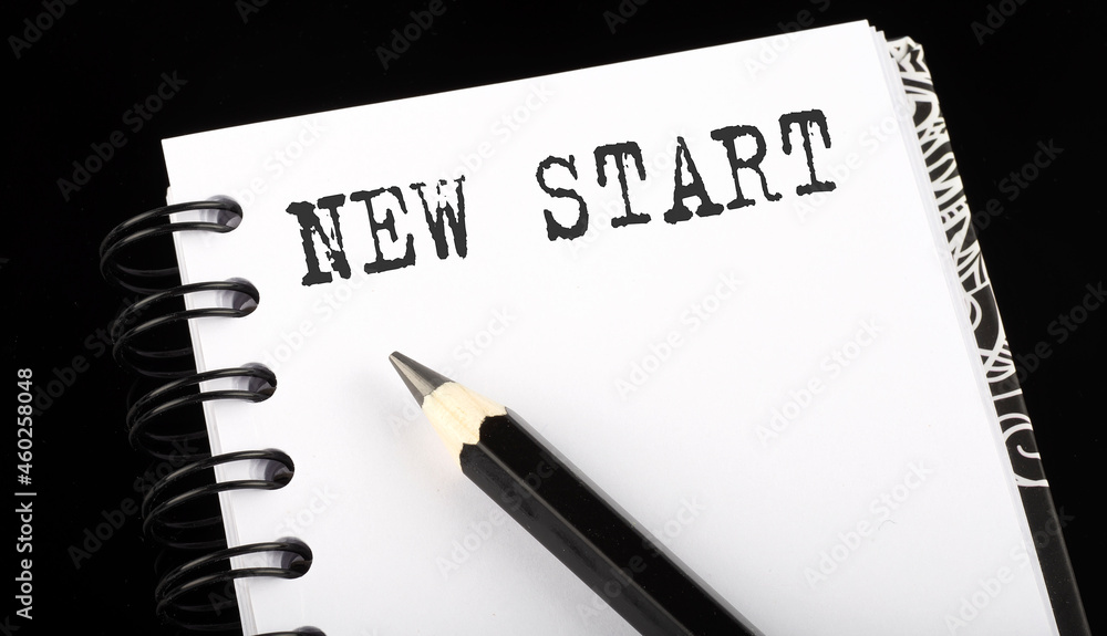 Aufkleber new start written text in small notebook on a black background