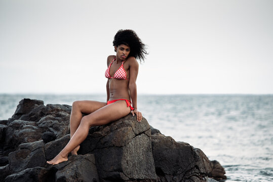 Woman sitting in rocks by the seashore