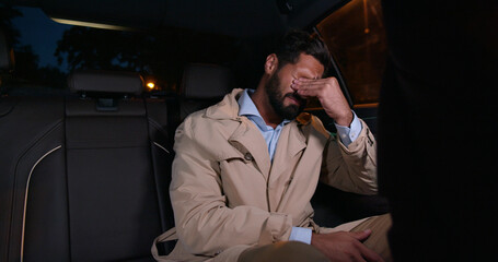 Young depressed businessman crying on backseat of car