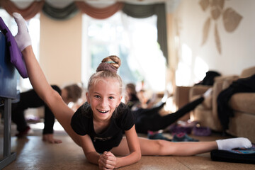 Girl gymnast smiling and stretching on training in sports camp
