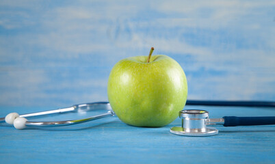 Green apple with stethoscope on the blue background.
