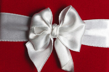 christmas background. close up of shiny white satin bow and red gift box 