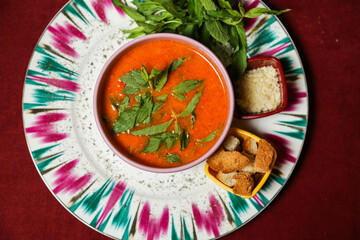 Bowl of sweet potatoes cream soup with fresh chive, roasted toast bread, pepper, carrot and garlic slate slab. View from above