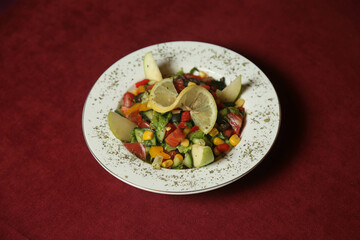 Vegetable salad with tuna in a red plate over dark blue slate, stone or concrete background. Top view with copy space.