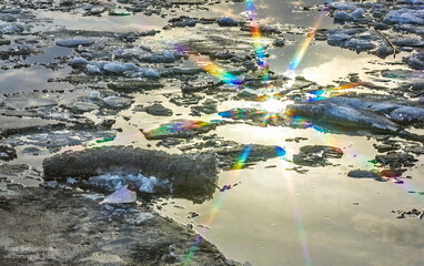 Melting ice in the river, in the water. Reflection of the sun with rays in the water. Spring ice drift on the river