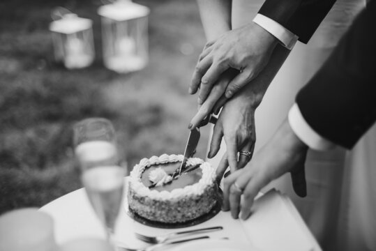 Black and white picture of bride and groom cut wedding cake.