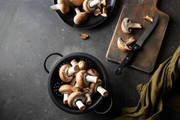 Whole and half cut portobello mushrooms on the kitchen table, with cut board, knife and napkin. Cooking process