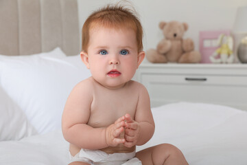 Cute little redhead baby on bed at home