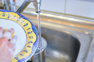 housewife washing dishes in the kitchen sink after the meal. cleaning and housework concept