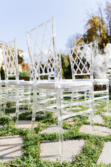Transparent plastic Chiavori chairs for guests on the street close-up. Autumn wedding ceremony on the street on the green lawn.