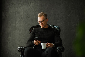 resting businessman sitting in a chair with a mobile phone and a cup of coffee 