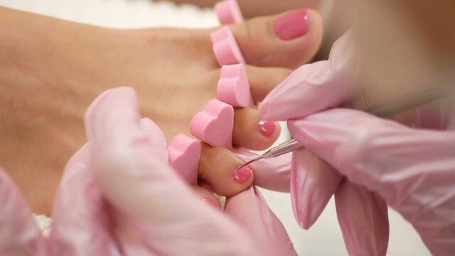 Close up of pedicure applying nail polish on toenails.