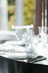 glass glasses and white plates. table setting in the interior of the restaurant. The decor of the festive table. In gray-silver tones with gold cutlery. Luxury wedding, party, birthday.