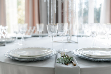 glass glasses and white plates. table setting in the interior of the restaurant. The decor of the festive table. In gray-silver tones with gold cutlery. Luxury wedding, party, birthday.