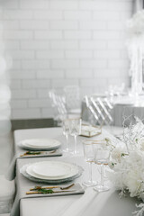 glass glasses and white plates. table setting in the interior of the restaurant. The decor of the festive table. In gray-silver tones with gold cutlery. Luxury wedding, party, birthday.