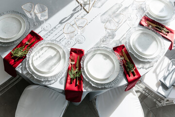 glass glasses and white plates. table setting in the interior of the restaurant. The decor of the festive table. In gray-silver tones with gold cutlery. Colored napkins.
