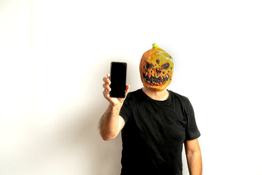 Man with pumpkin mask using a smart phone on a white background