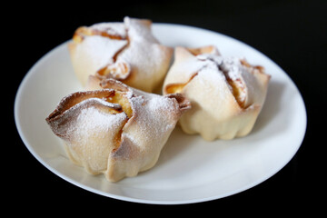 Soffioni сakes in white plate on black background. Italian ricotta cheese and lemon dessert