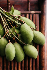 Close up of fresh small green Mangos on a wooden plate, fruit picnic in nature