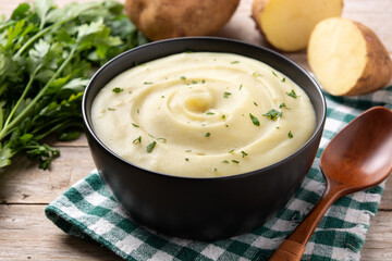 Mashed potatoes in a bowl on wooden table. 