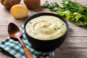 Mashed potatoes in a bowl on wooden table. 