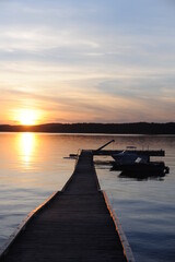 Sunset with wooden pier or deck on a calm day with sun reflecting in the sea