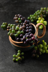 grape bunches in ceramic cups on gray background