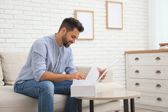 Man Unpacking Parcel At Home. Online Shopping