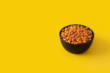 White beans in tomato sauce in bowl on yellow background. Copy space