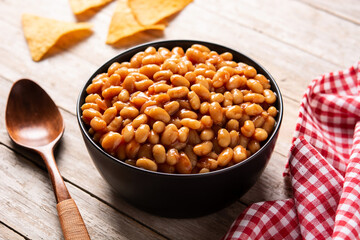White beans in tomato sauce in bowl on wooden table