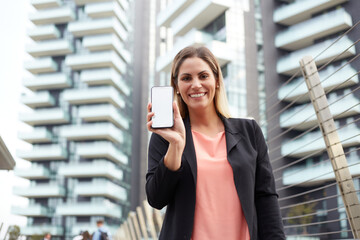 Fototapeta premium Smiling businesswoman holding blank screen's mobile in urban environment