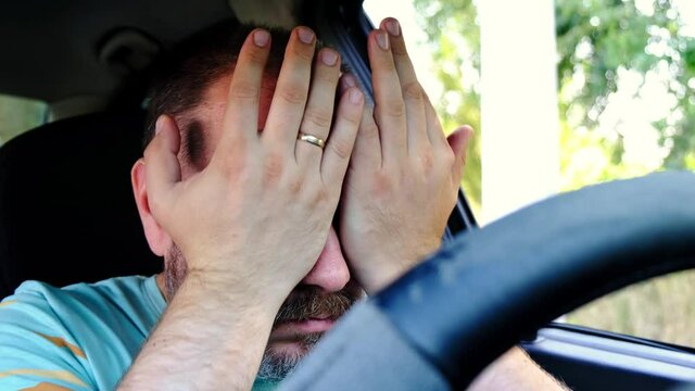 A man does self-massage of his eyes in the car. Fatigue on the road, while driving.