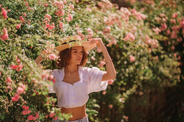 Outdoor summer portrait of young beautiful woman wearing trendy  straw hat, vintage style white...
