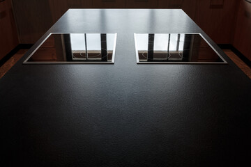 Large clean black worktop with two glass ceramic hobs. Backlighting. Selective focusing.