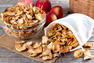 Homemade sun-dried organic apple slices, crispy apple chips, on an old rustic wooden table with fresh apple. Healthy eating.